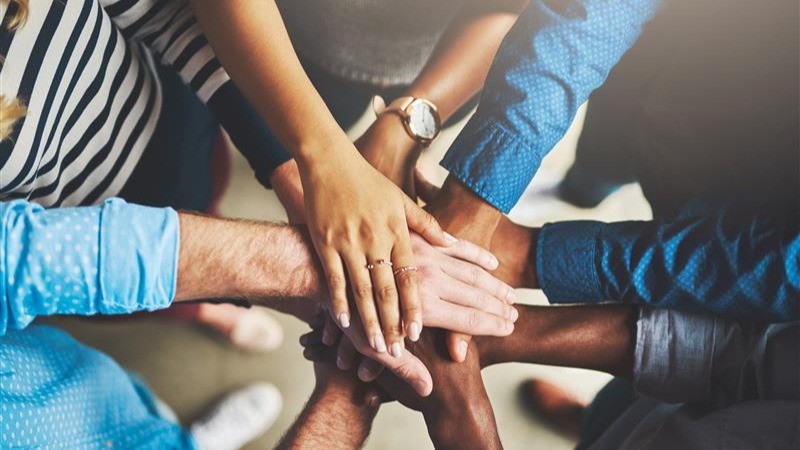 Picture of hands together in the middle of a circle, to show working together.